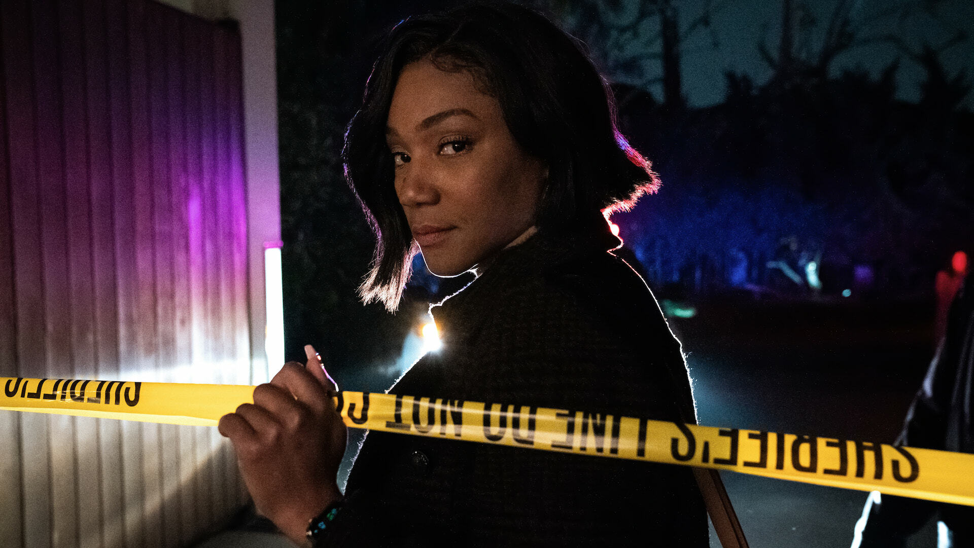 Actor Tiffany Haddish poses from behind a strip of police tape in a still from 
