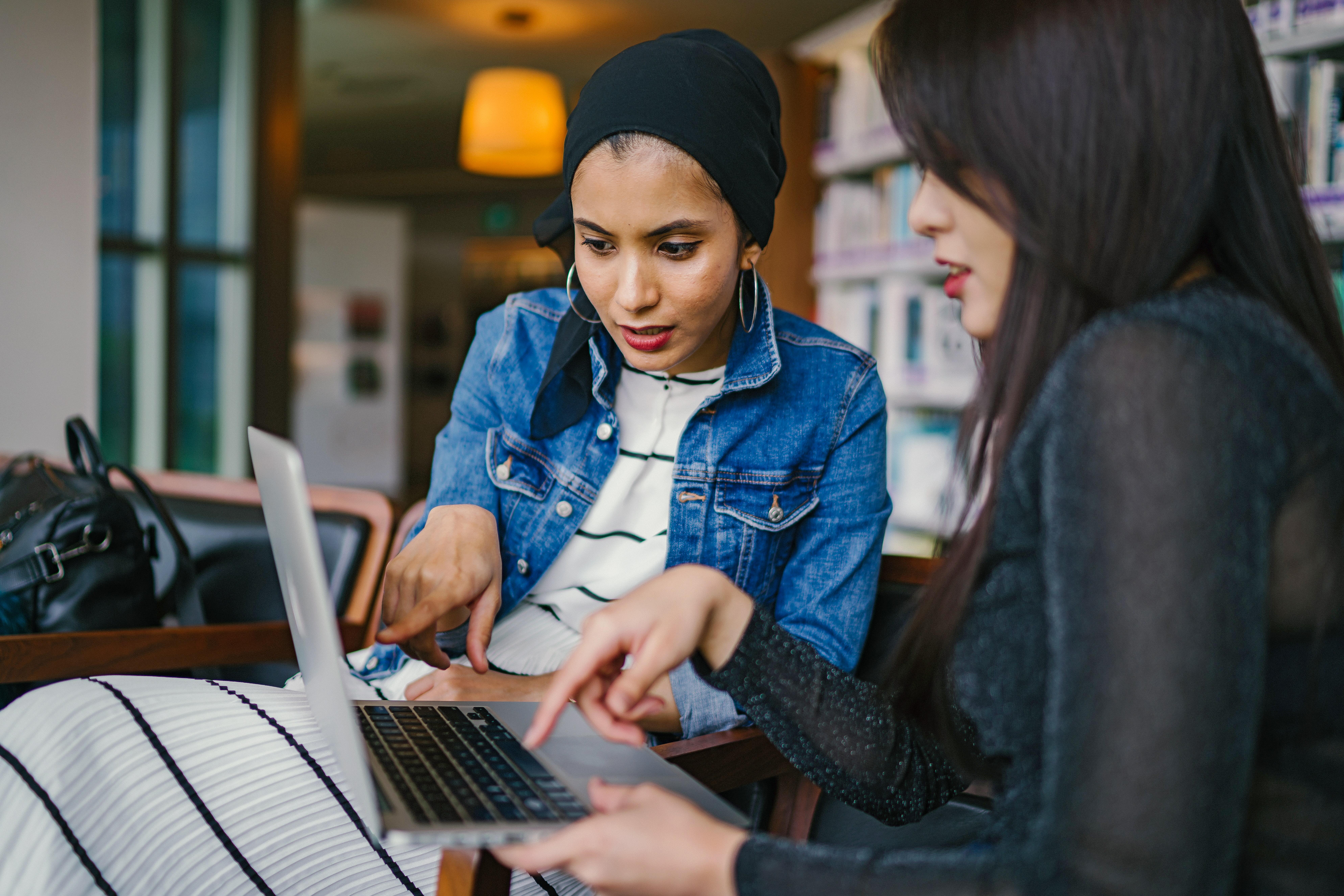 Two people pointing at laptop