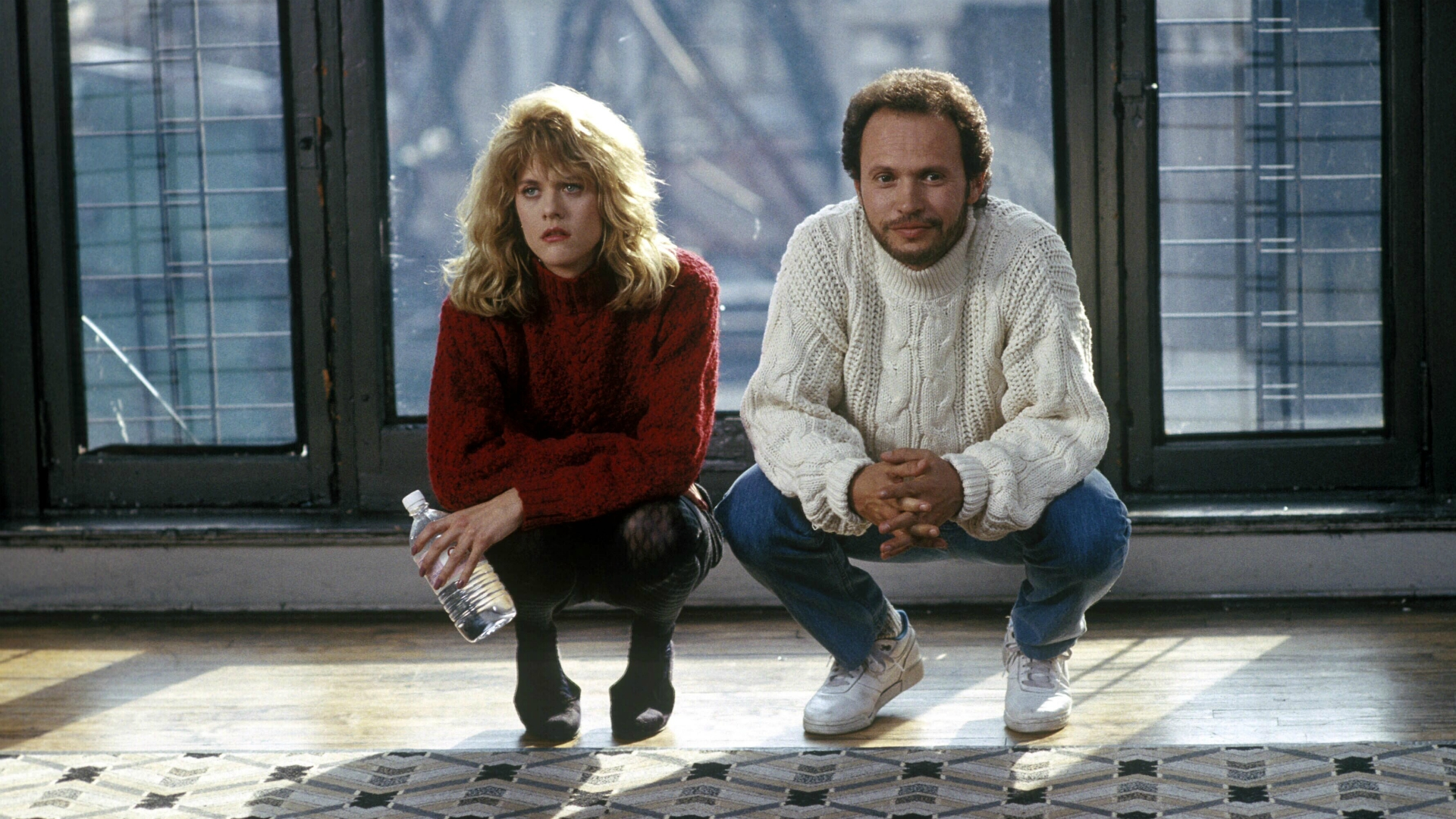 A man and woman crouch down in front of a window.
