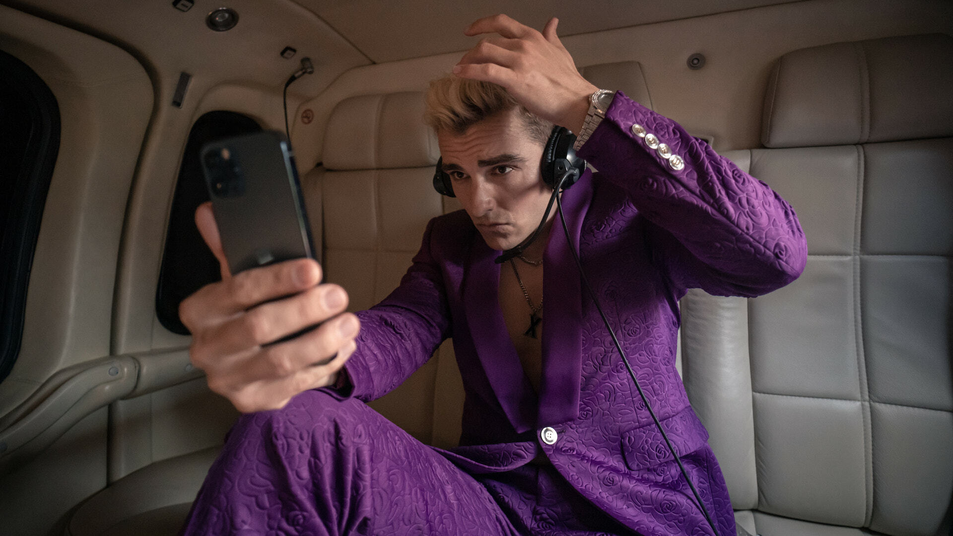 A man in a purple suit with bleach-blond hair checks himself out in his phone; a still from "The Afterparty."