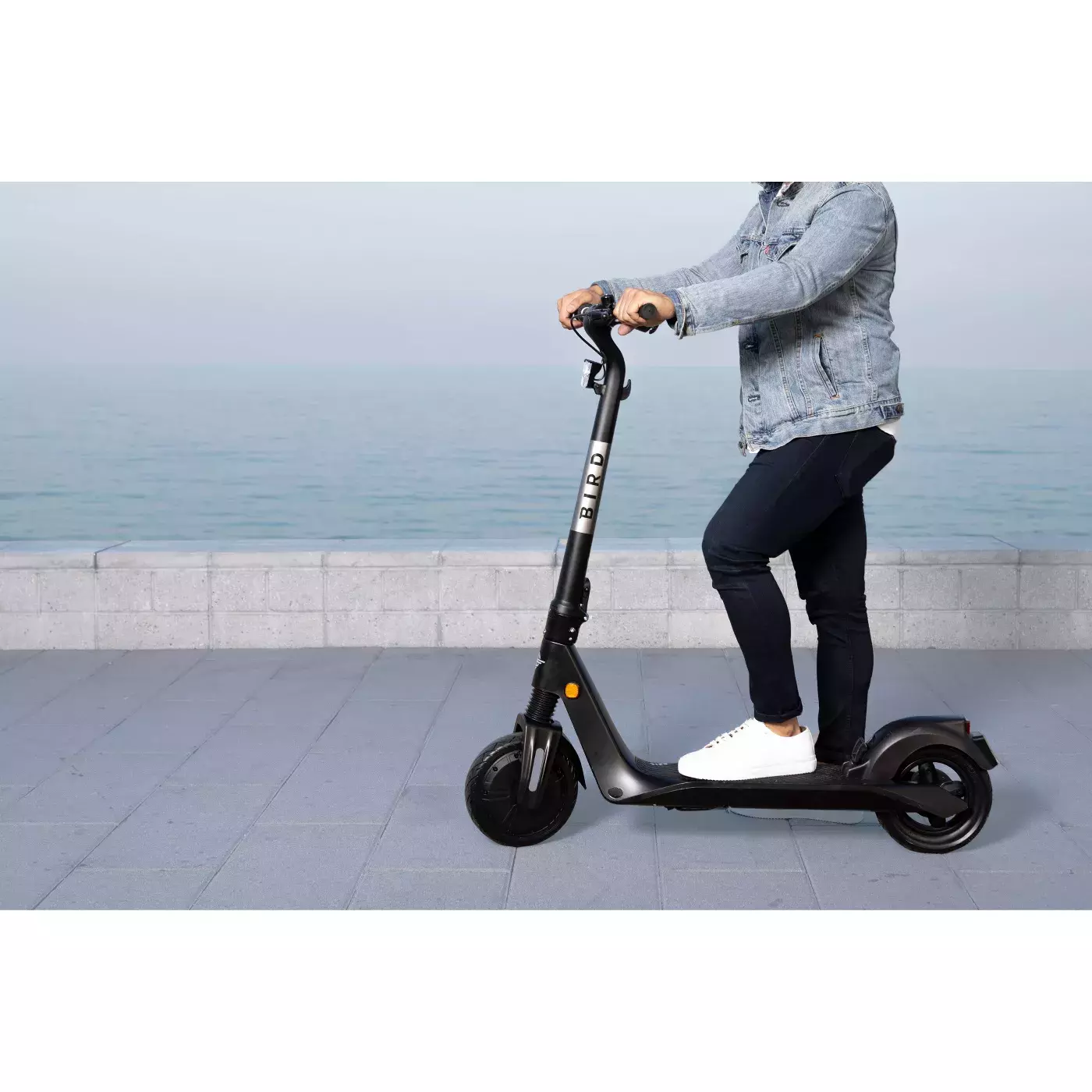 A person standing on a scooter.