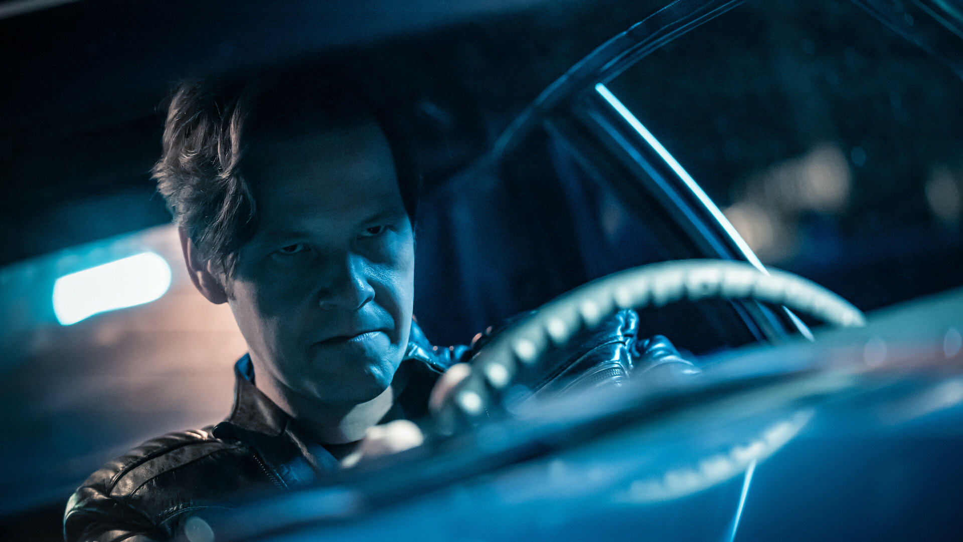 Close up on man with a determined expression behind the wheel of a car; a still from "The Afterparty."