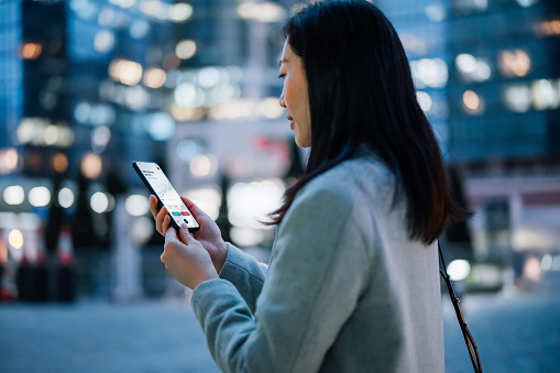 Young woman checks stocks on her phone.