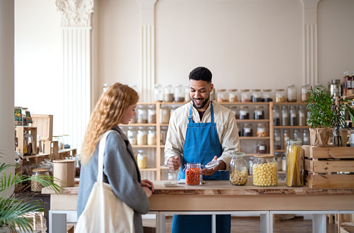 Man helps woman in his shop.