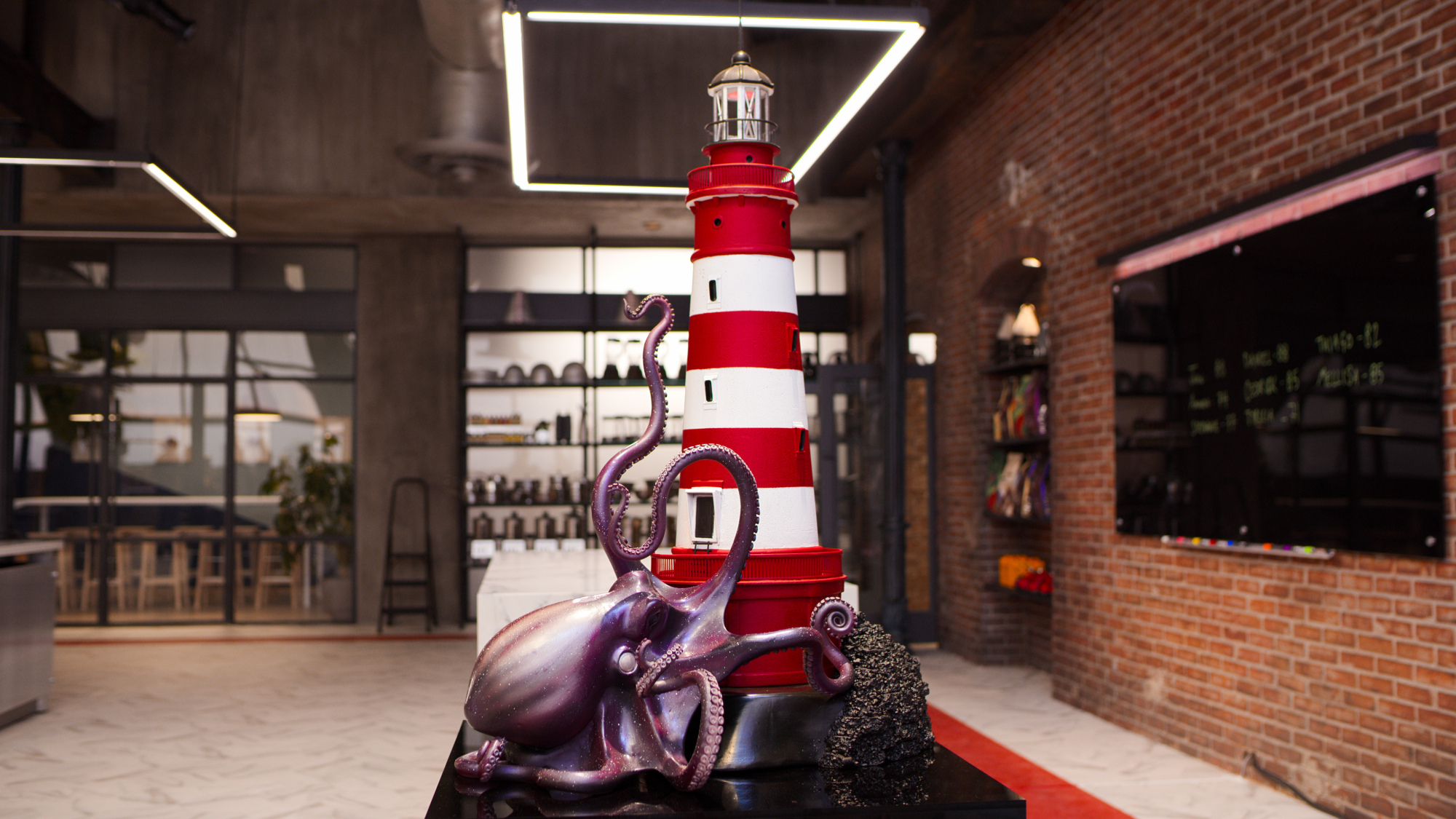 A chocolate sculpture of an octopus climbing up the bottom of a lighthouse.