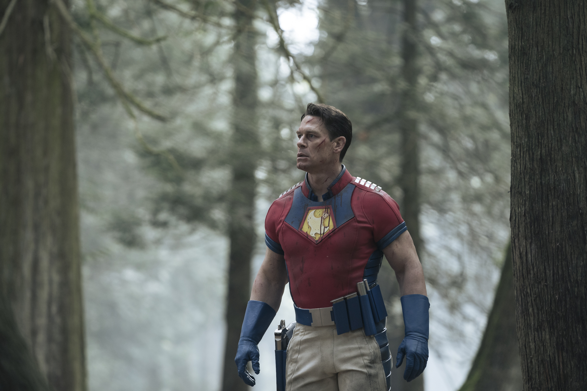The superhero Peacemaker, as portrayed by John Cena, walking through the woods.