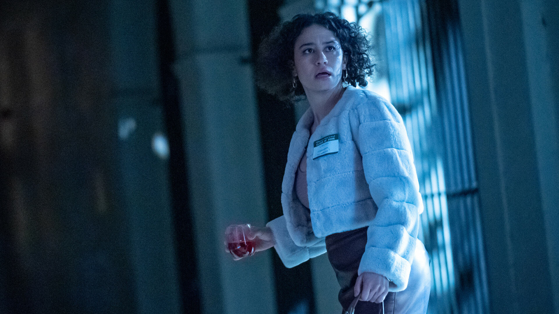 A woman stands frozen in fear in a high school hallway; a still from "The Afterparty."