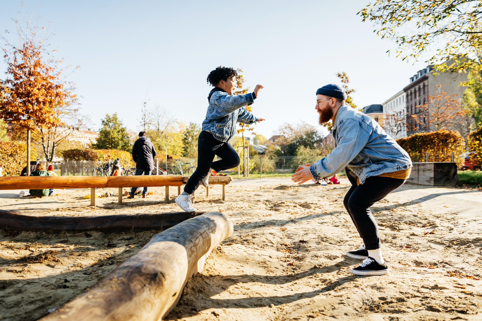 An adult and child joyfully play at an outdoor park.