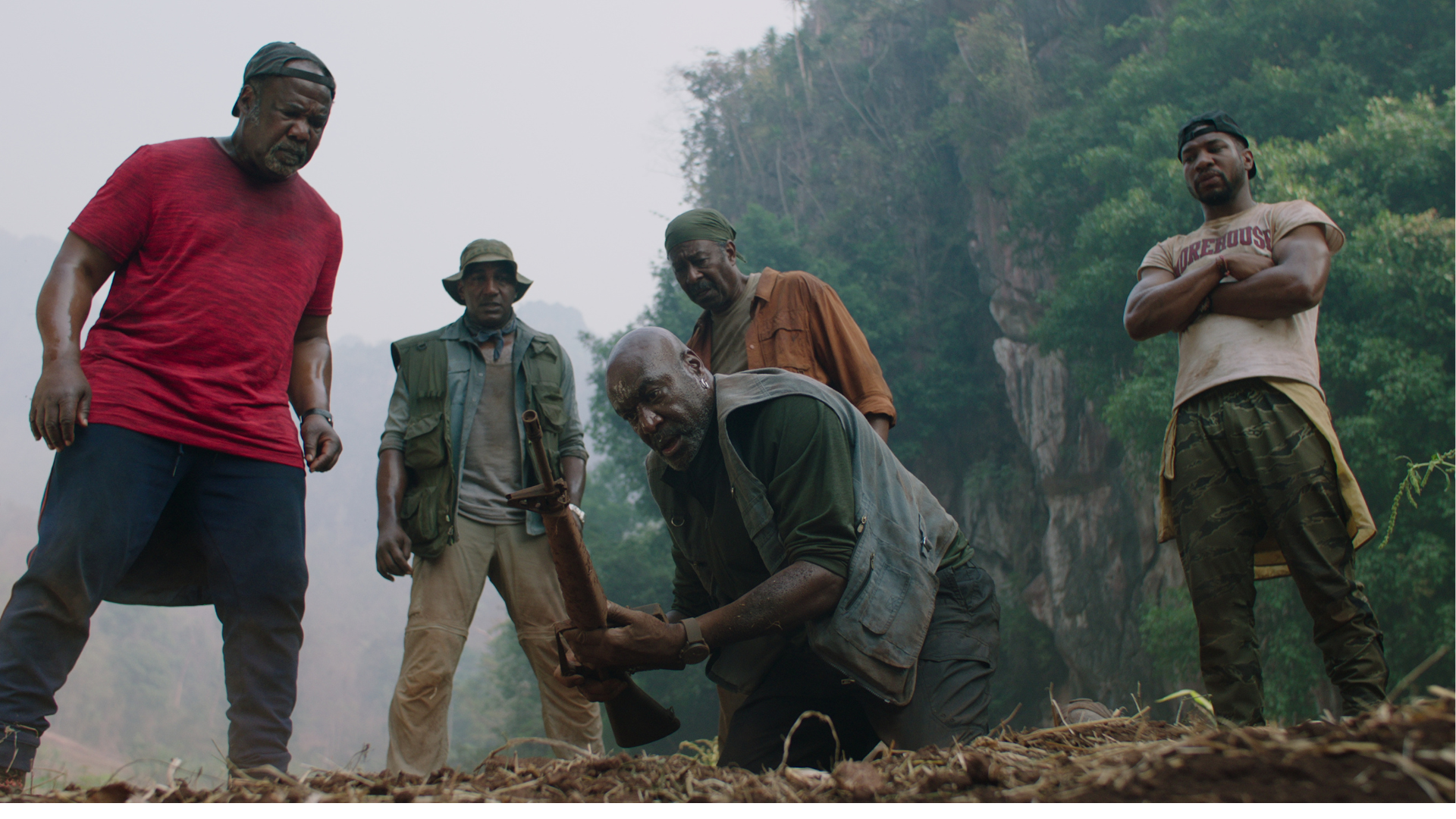 Five Black men stand in a circle, wearing modern attire and looking concerned.