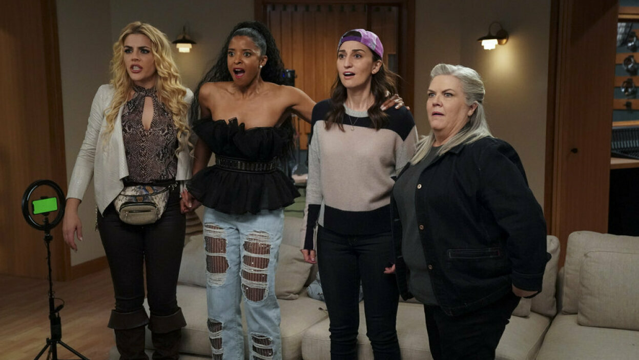 Four women stand in a recording studio. 
