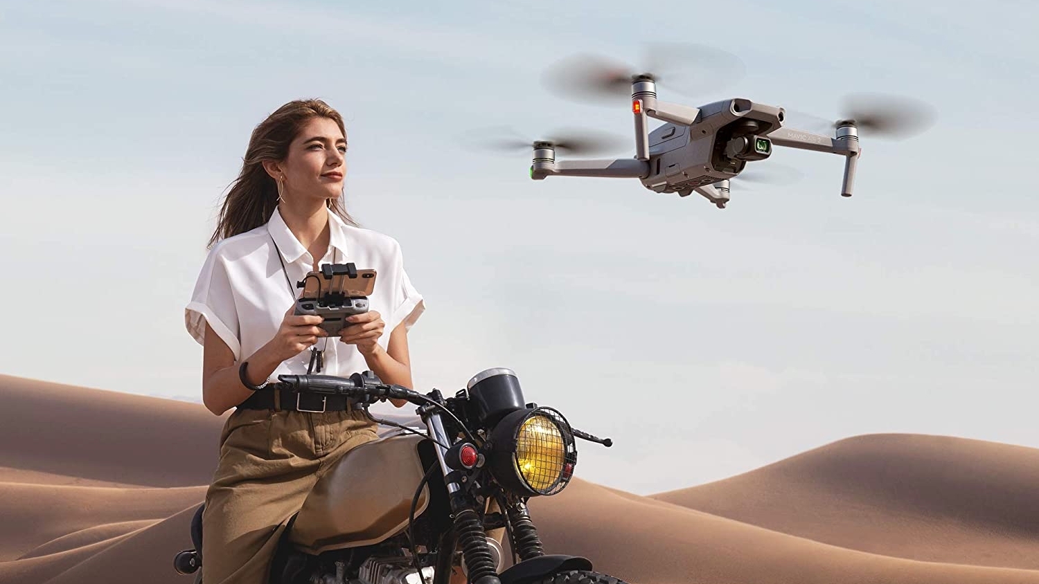 Person sitting on bike in desert flying a drone