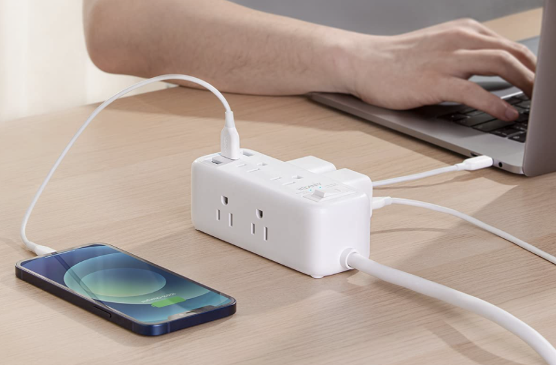 person at laptop next to a power strip