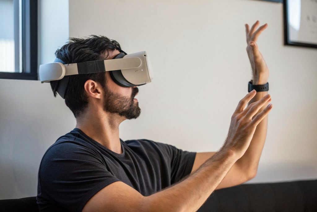 Man wearing a white virtual reality headset with his hands up in the air