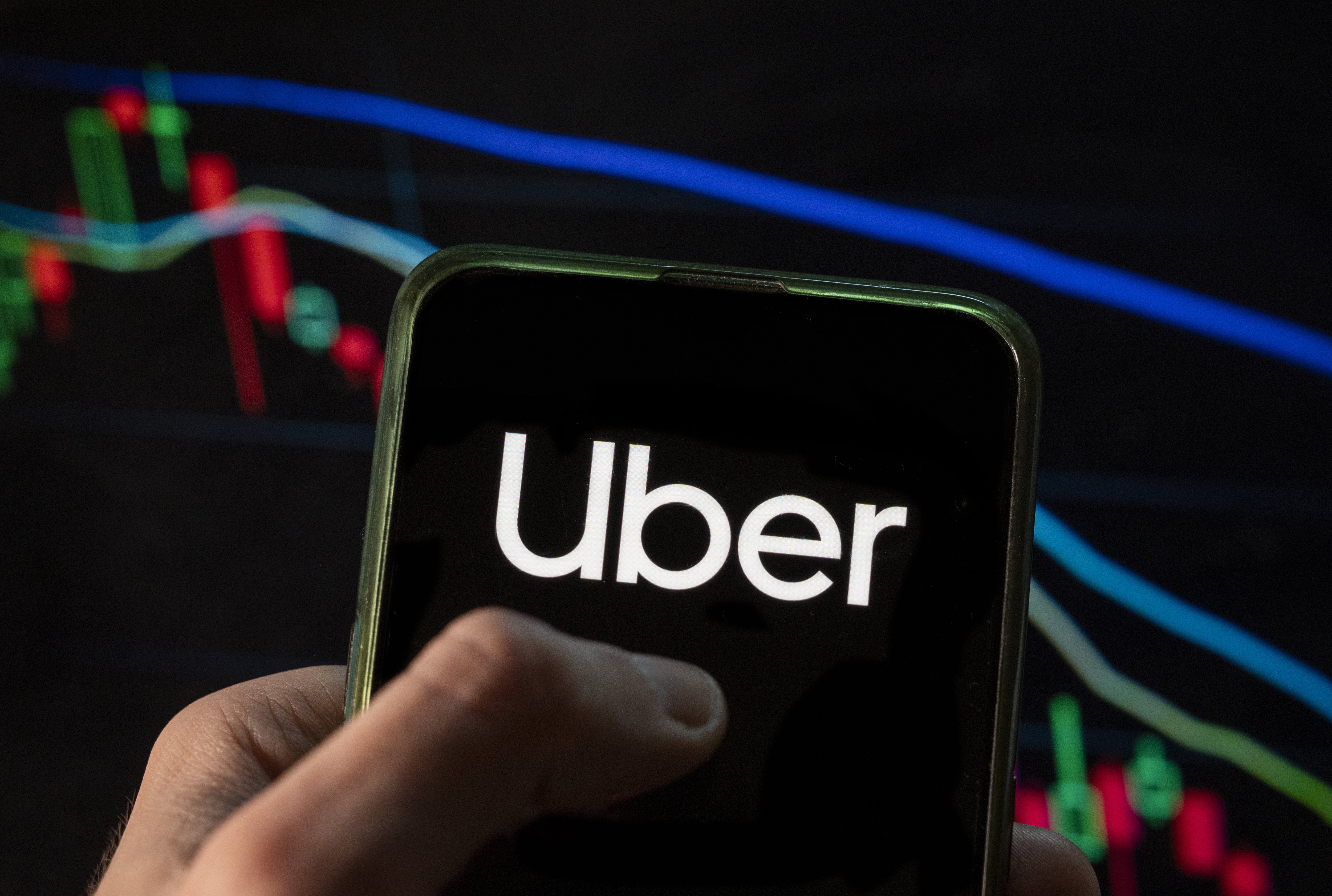 The Uber logo in front of a graph with trend lines.