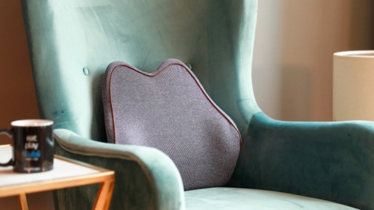 Purple cushion on green armchair next to coffee mug on side table