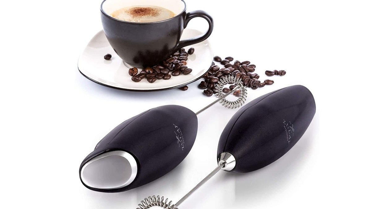 Cup of coffee next to milk frother wand