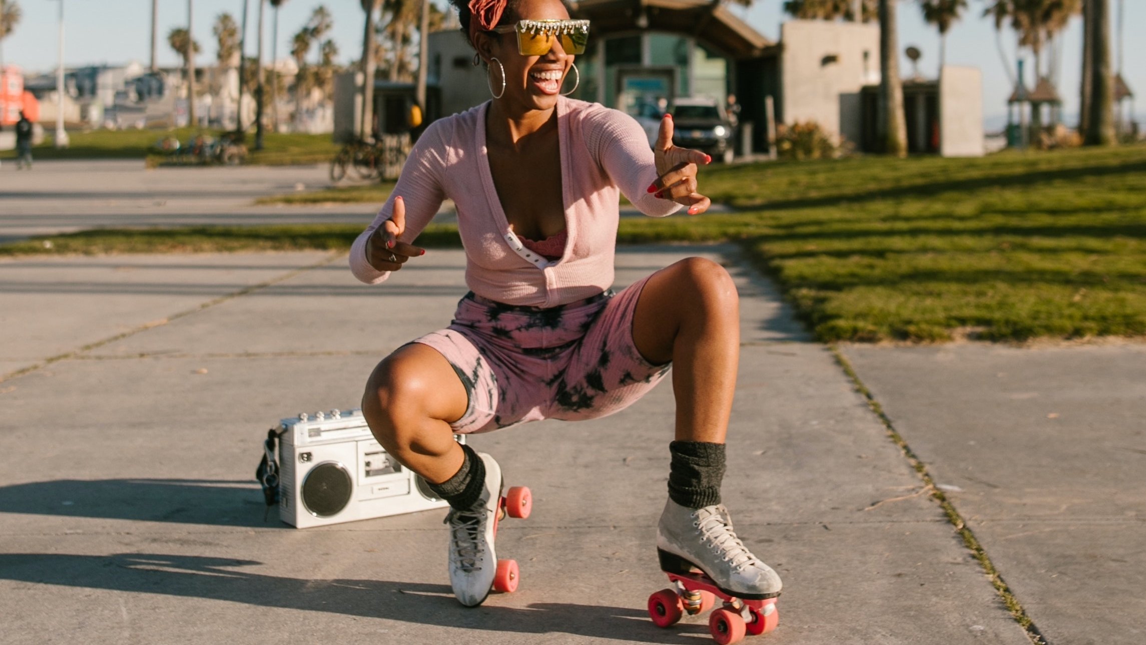 Person crouching and posing on roller skates with boombox behind them