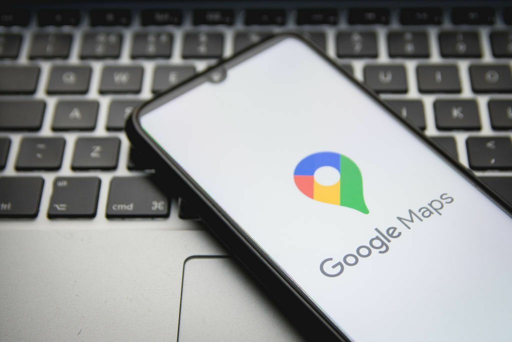 The Google Maps icon on a phone resting on a laptop keyboard.