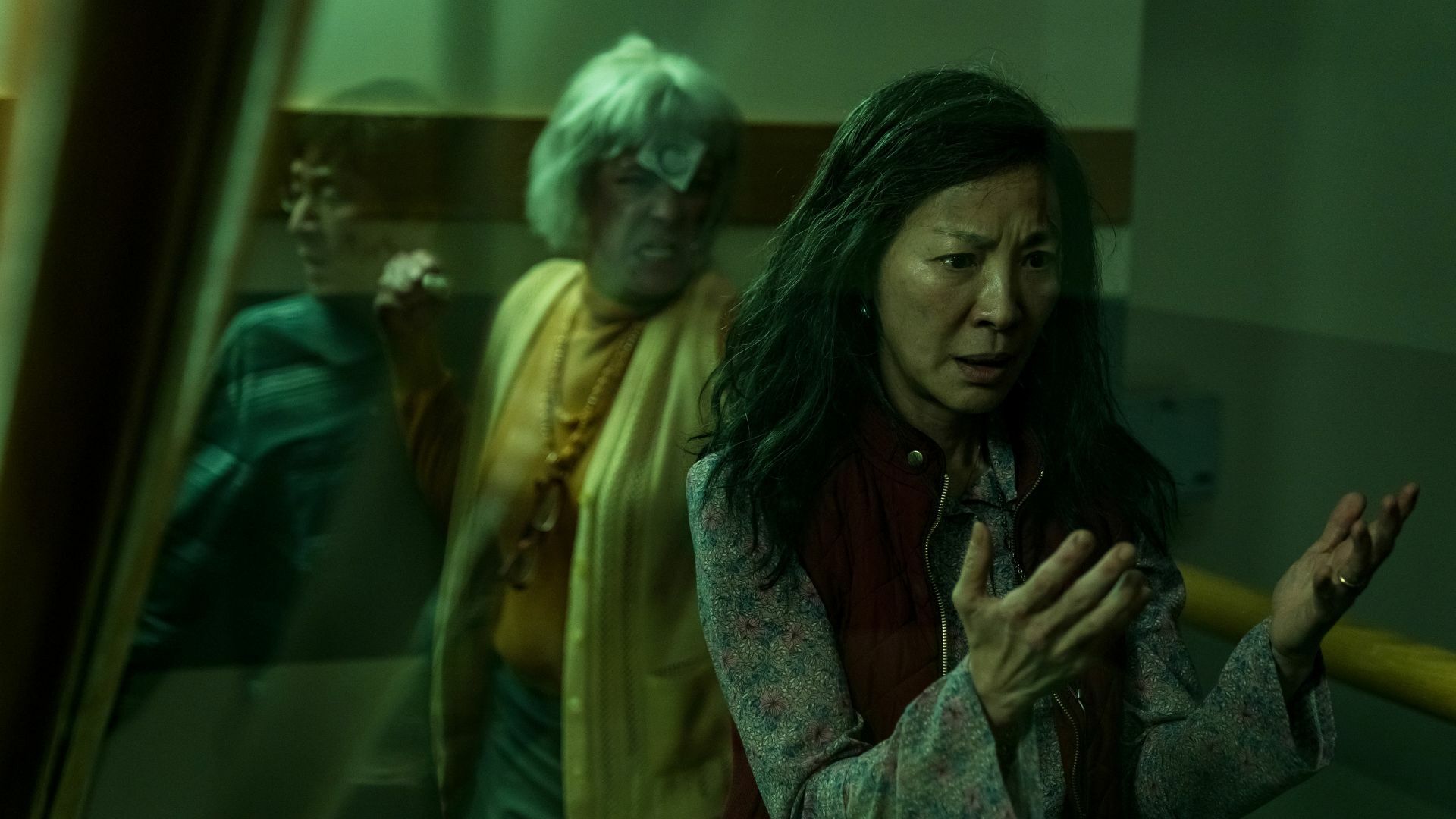 A woman looks at her hands, confused, while a woman in yellow barrels toward her for a fight.