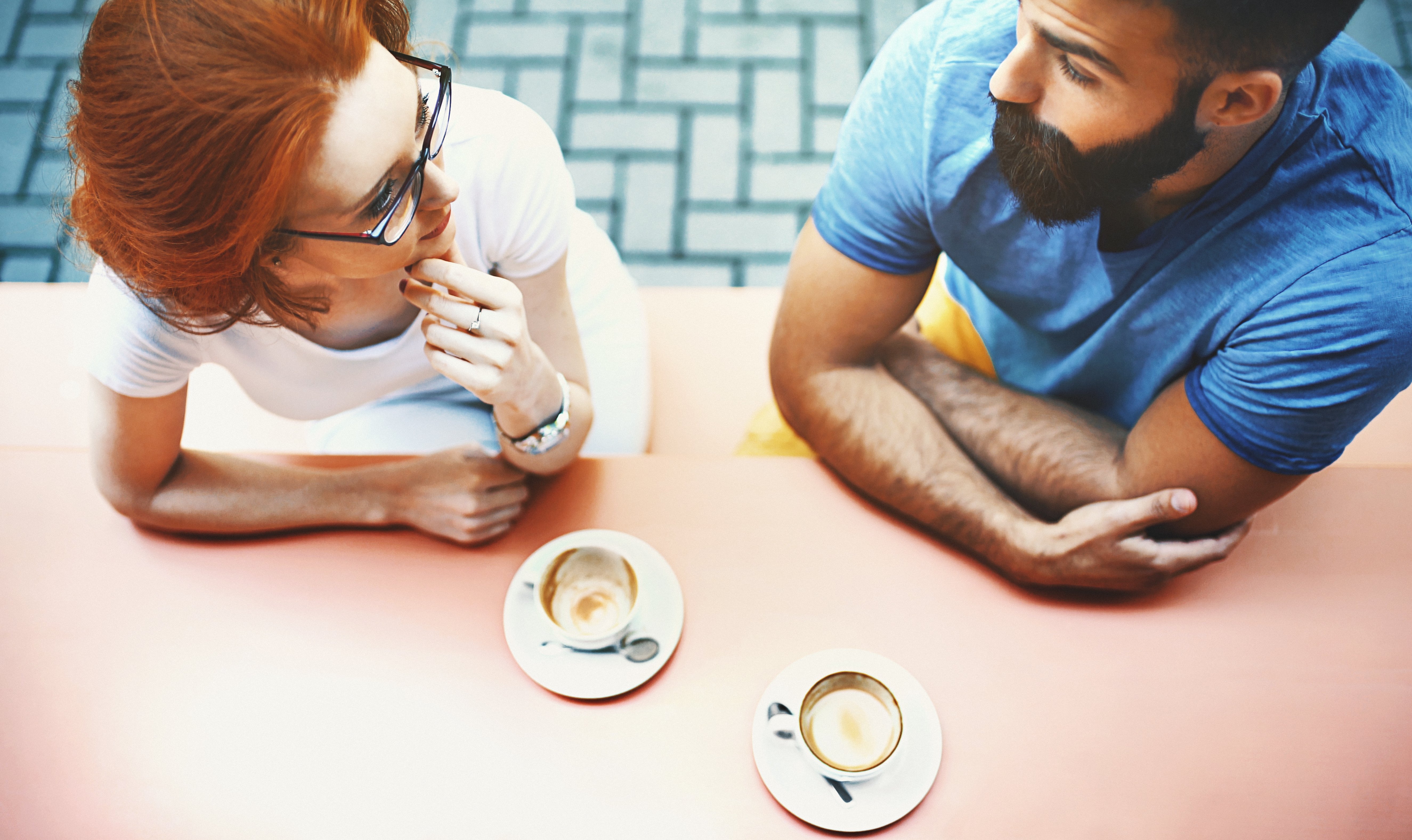 two people sitting at a table, each with coffee cups
