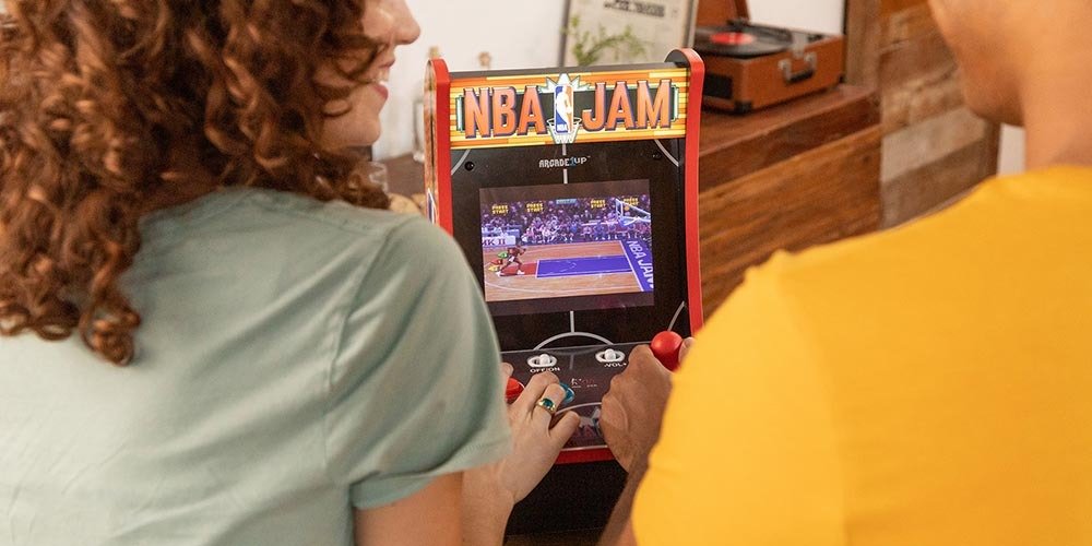 Backs of two people playing NBA Jam game