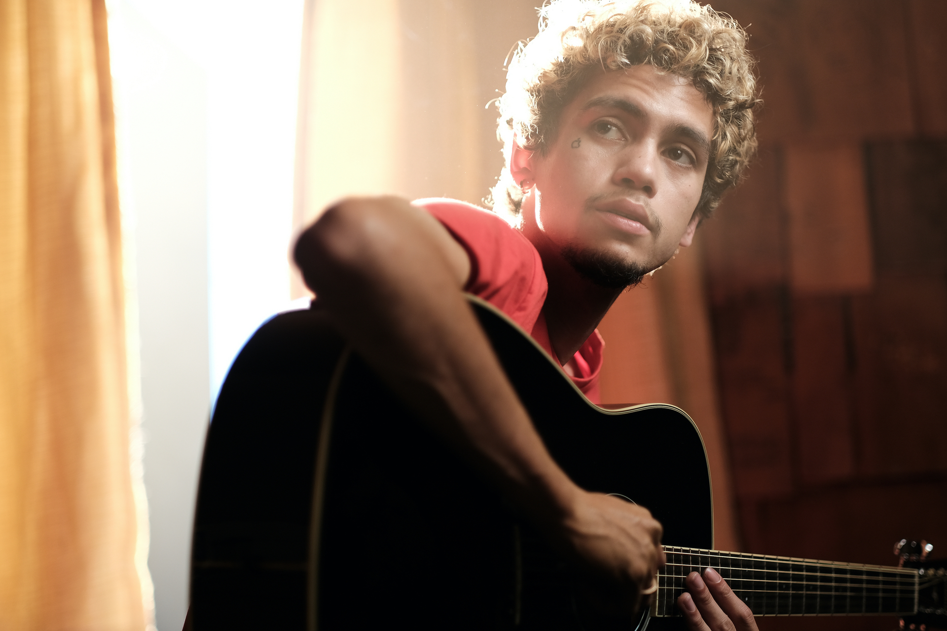 Dominic Fike playing the acoustic guitar on 