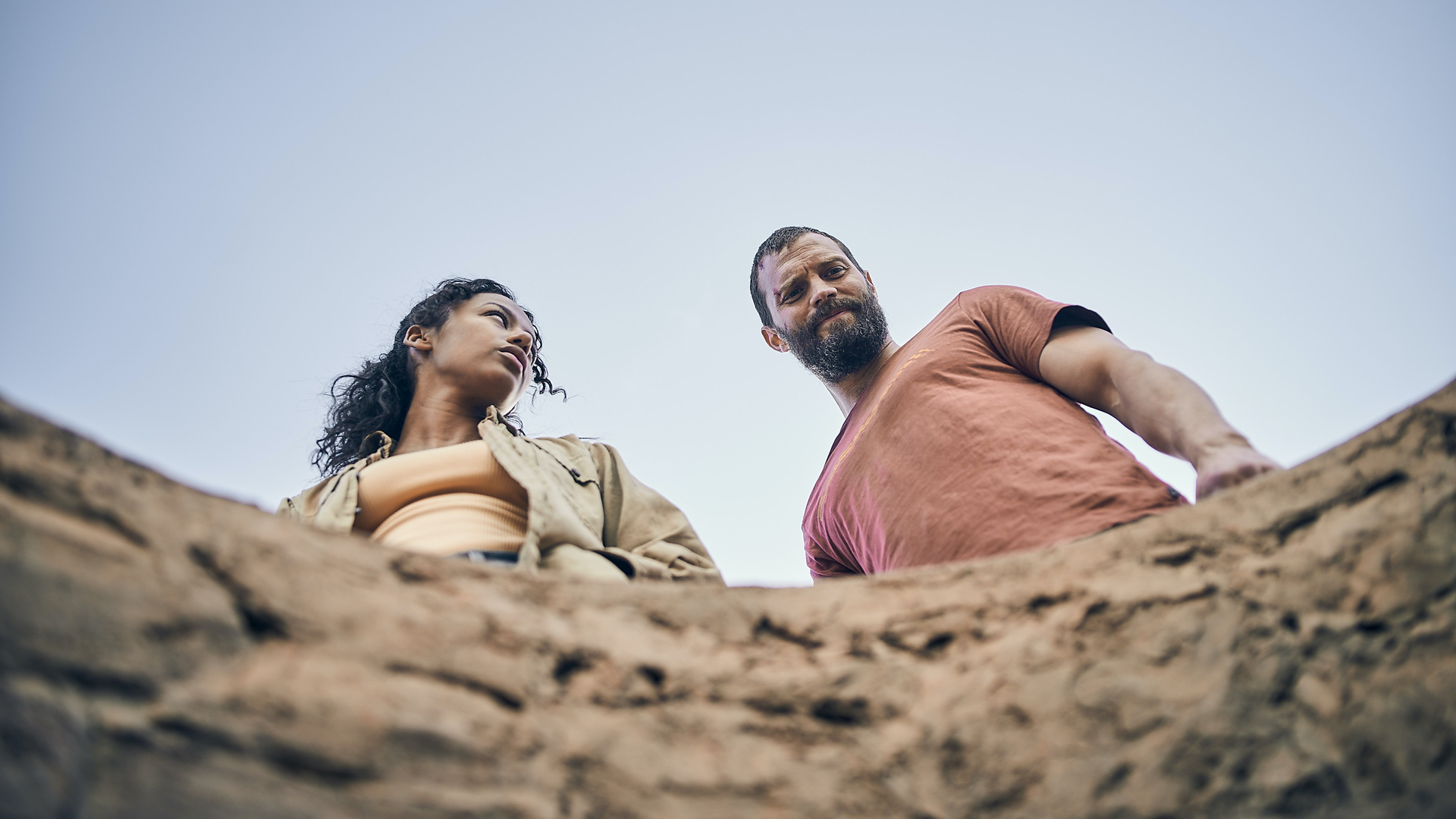 A man and woman look down into a well; a still from 