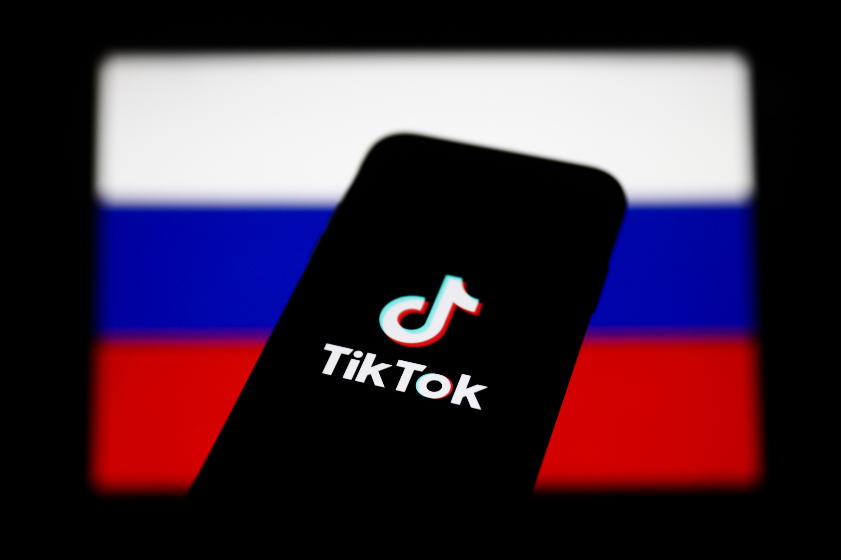 A smartphone showing the TikTok logo overlaid on the Russian flag.