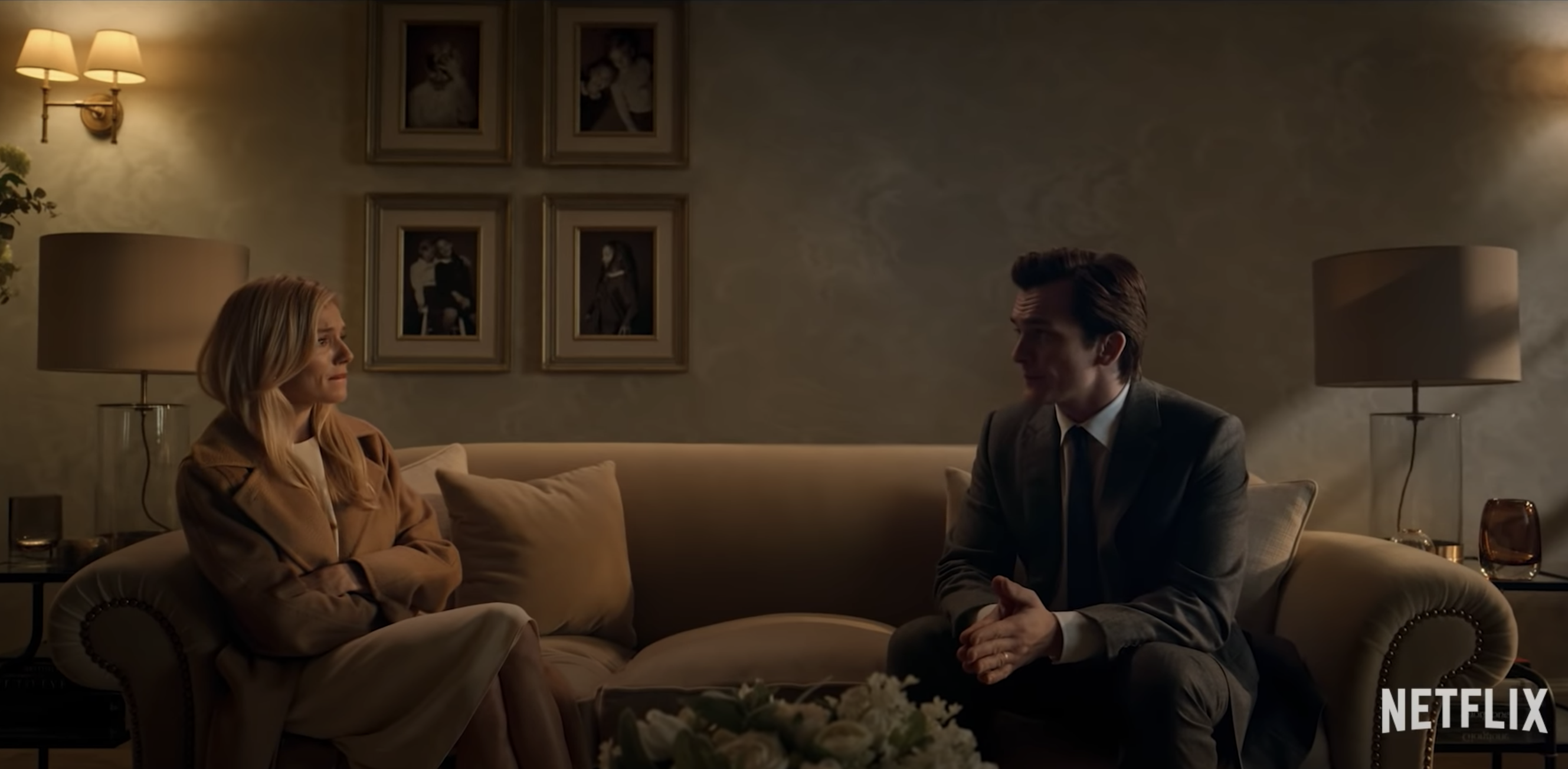 A man and woman regard each other tensely from opposite ends of a couch; still from 