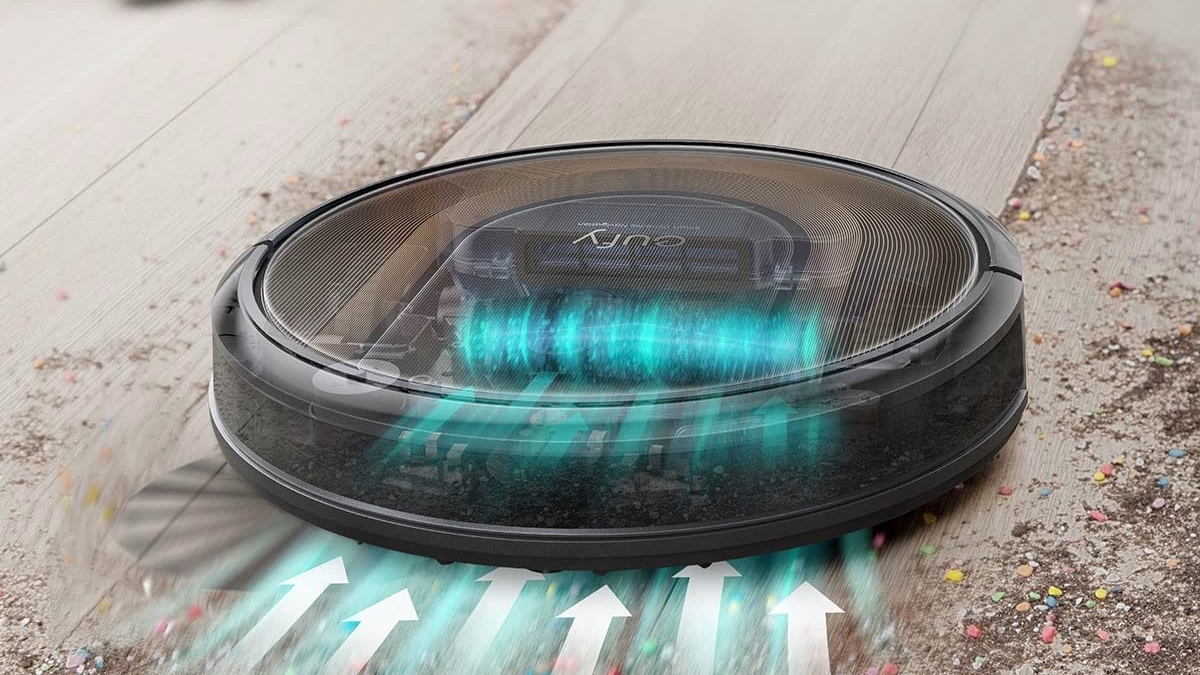 Black robot vacuum sucking up m&m crumbs on wooden floor