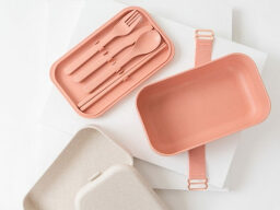 Pink and white lunchboxes with utensils strapped to inside of lid