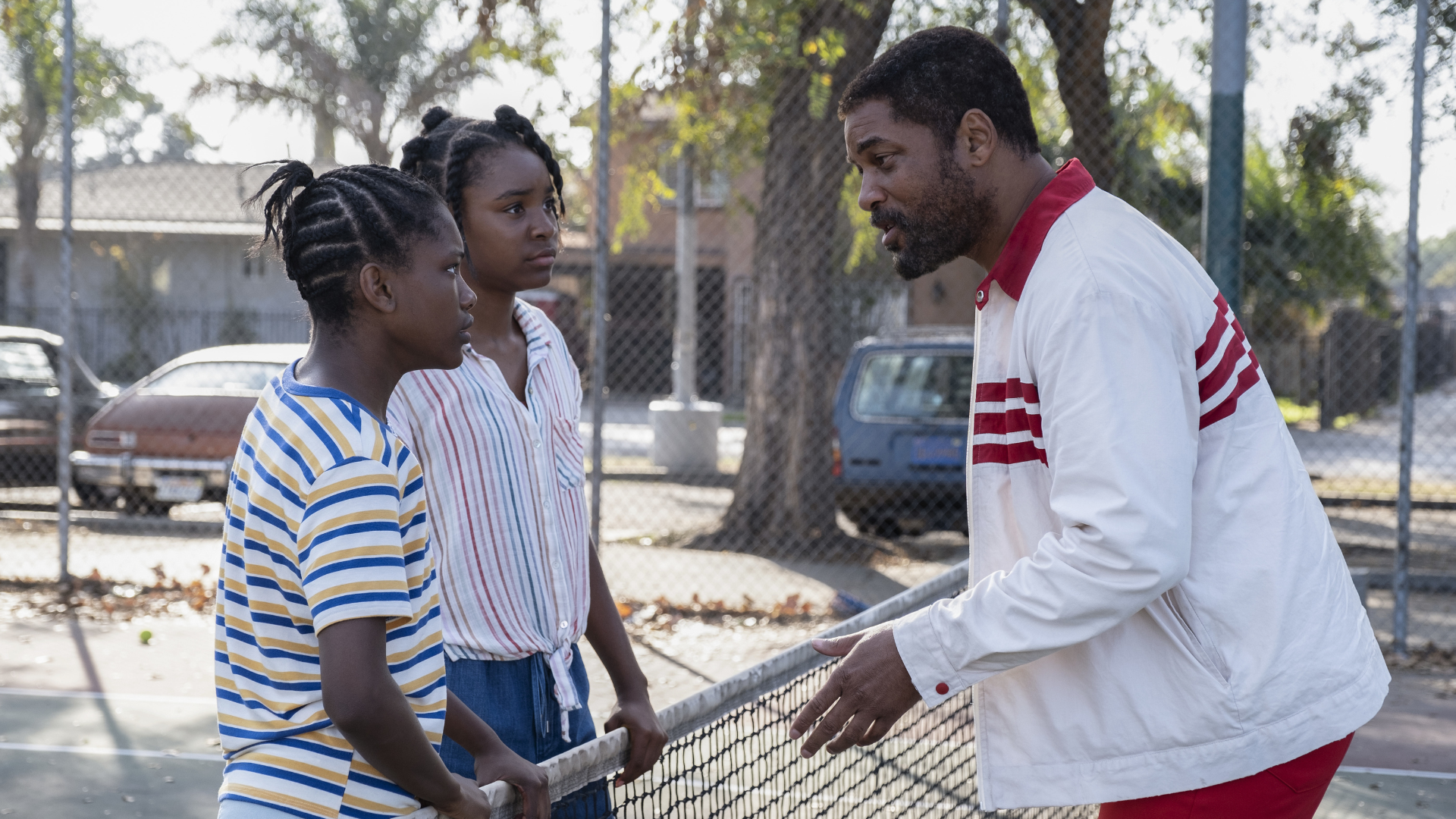 Will Smith playing Serena and Venus' dad, Richard Williams, talks strategy over a tennis net.