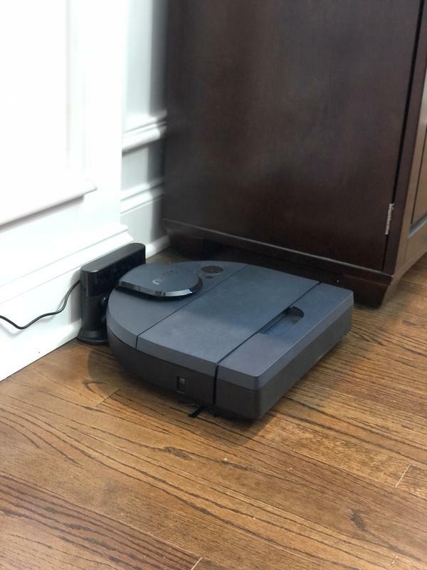 robot vacuum on dock next to a piece of furniture