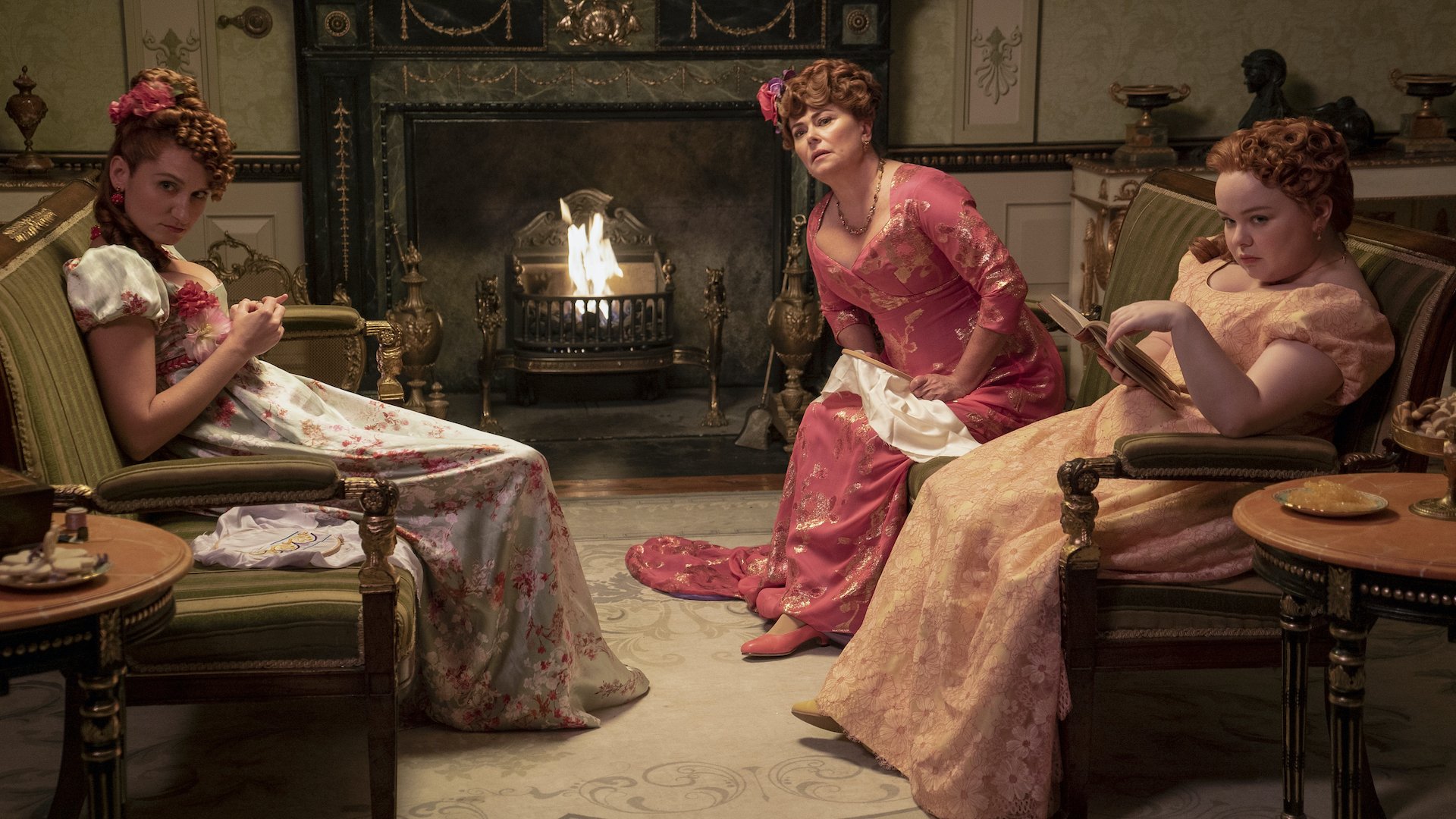 Three women in Regency gowns, looking disgruntled as they sit on sofas; still from "Bridgerton."