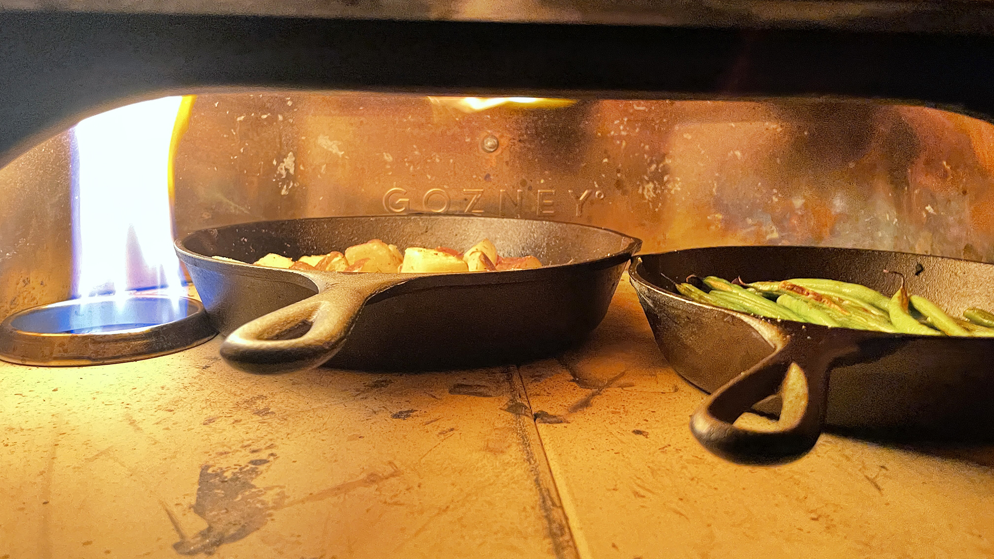 potatoes and green beans in cast irons skillets inside gozney dome