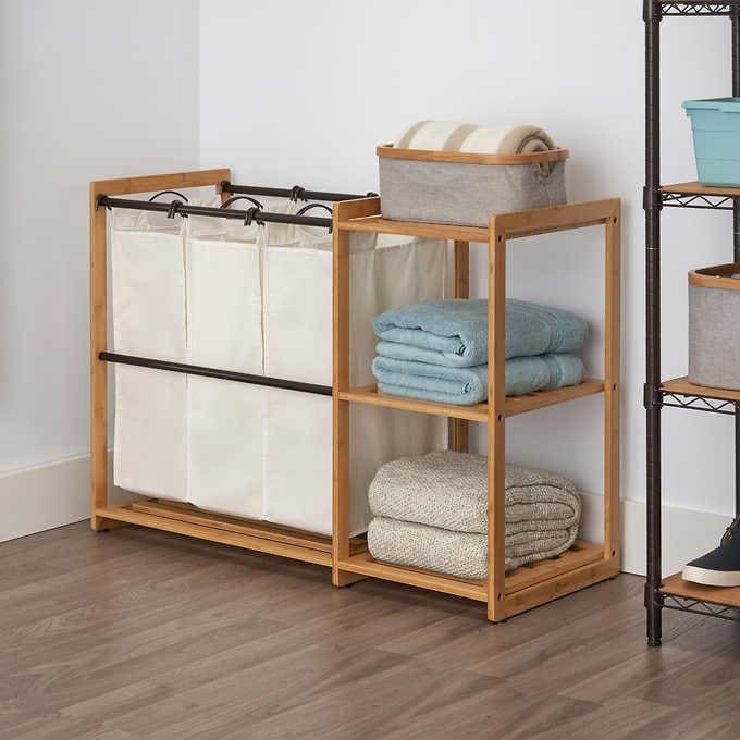 Wooden Laundry center with shelves, towels, and laundry bags