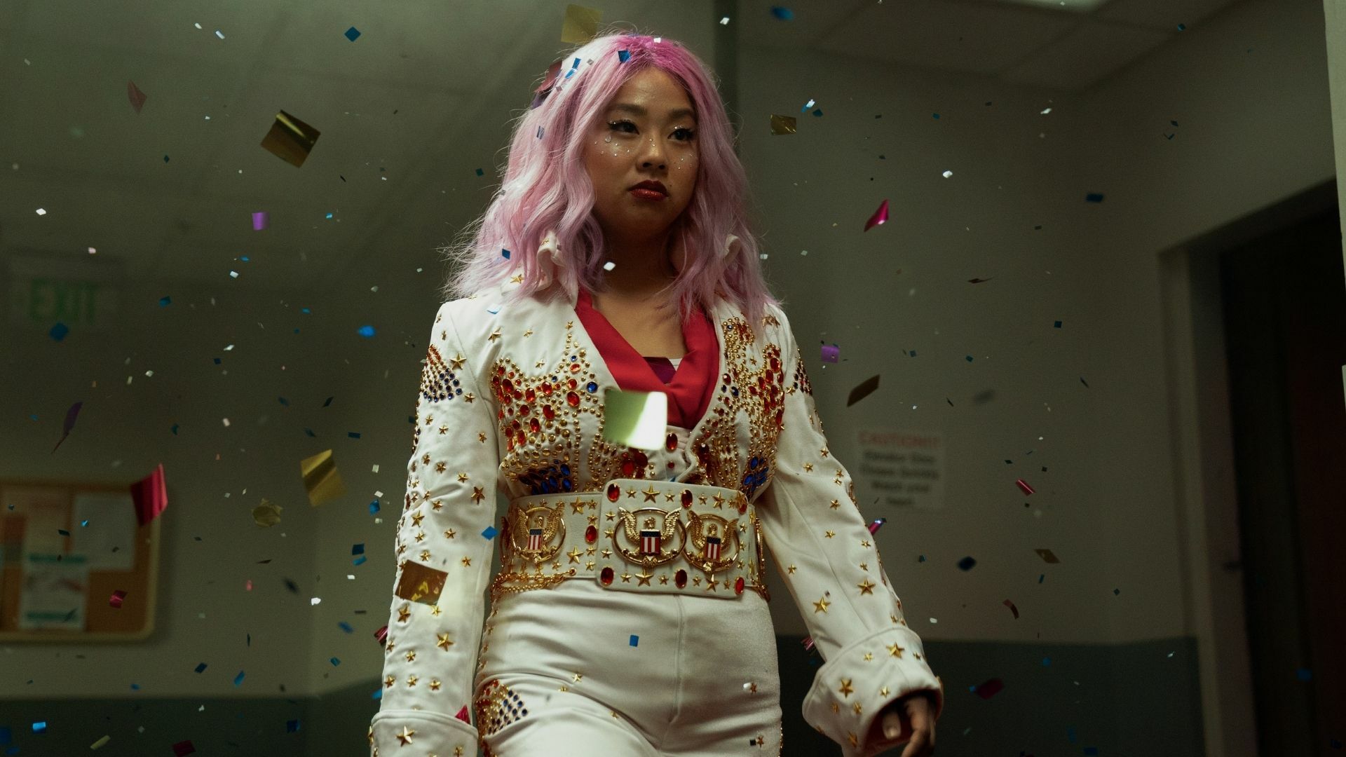 A pretty Asian girl with pink hair is dressed as Elvis Presley.