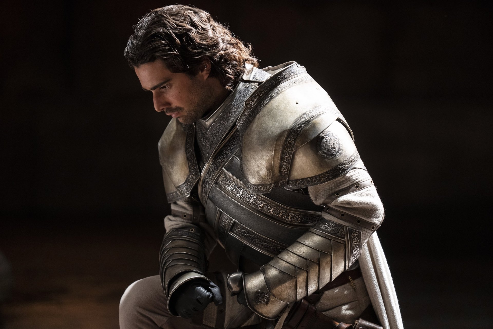A kneeling man in ornate armor.