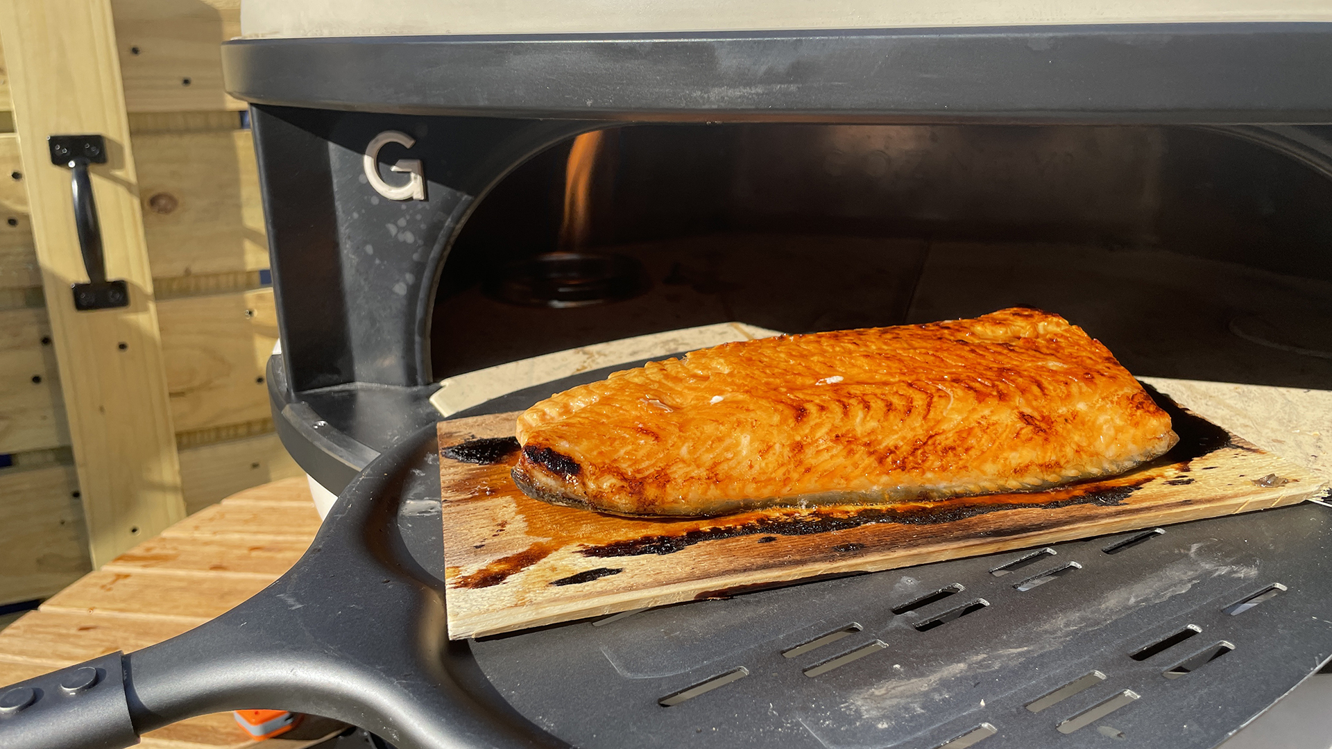 Salmon after being cooked in Gozney dome on a wood plank in front of the oven
