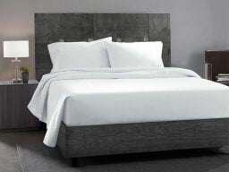 White and grey bed next to matching bedside table with lamp