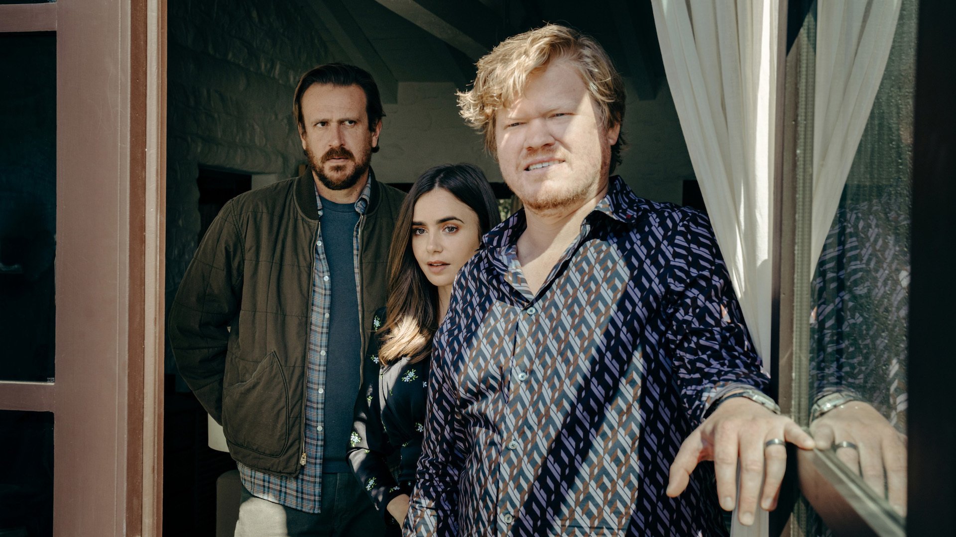 Left to right: Jason Segel, Lily Collins, and Jesse Clemons looking out the window in “Windfall.”