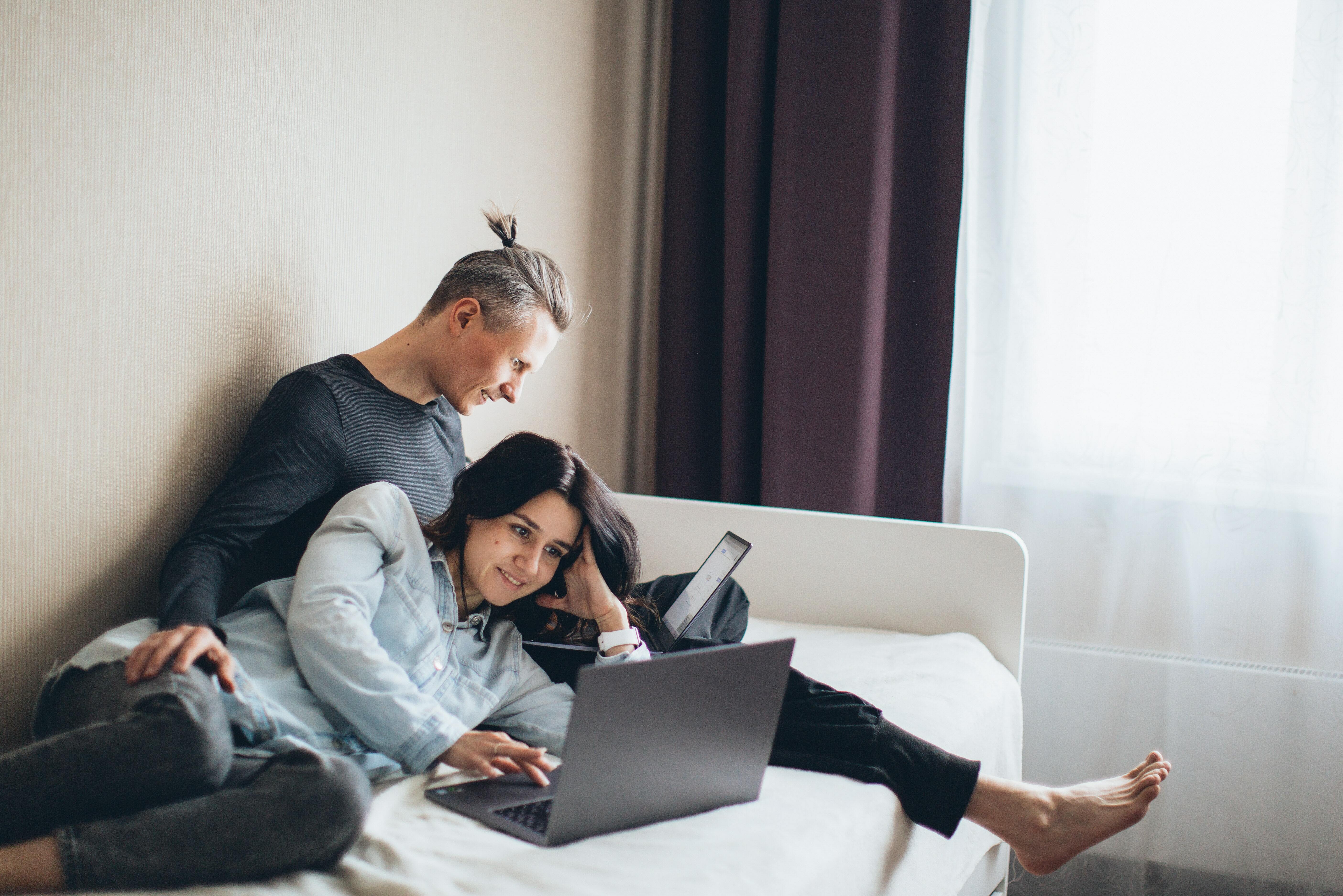 Couple sat on bed with laptop