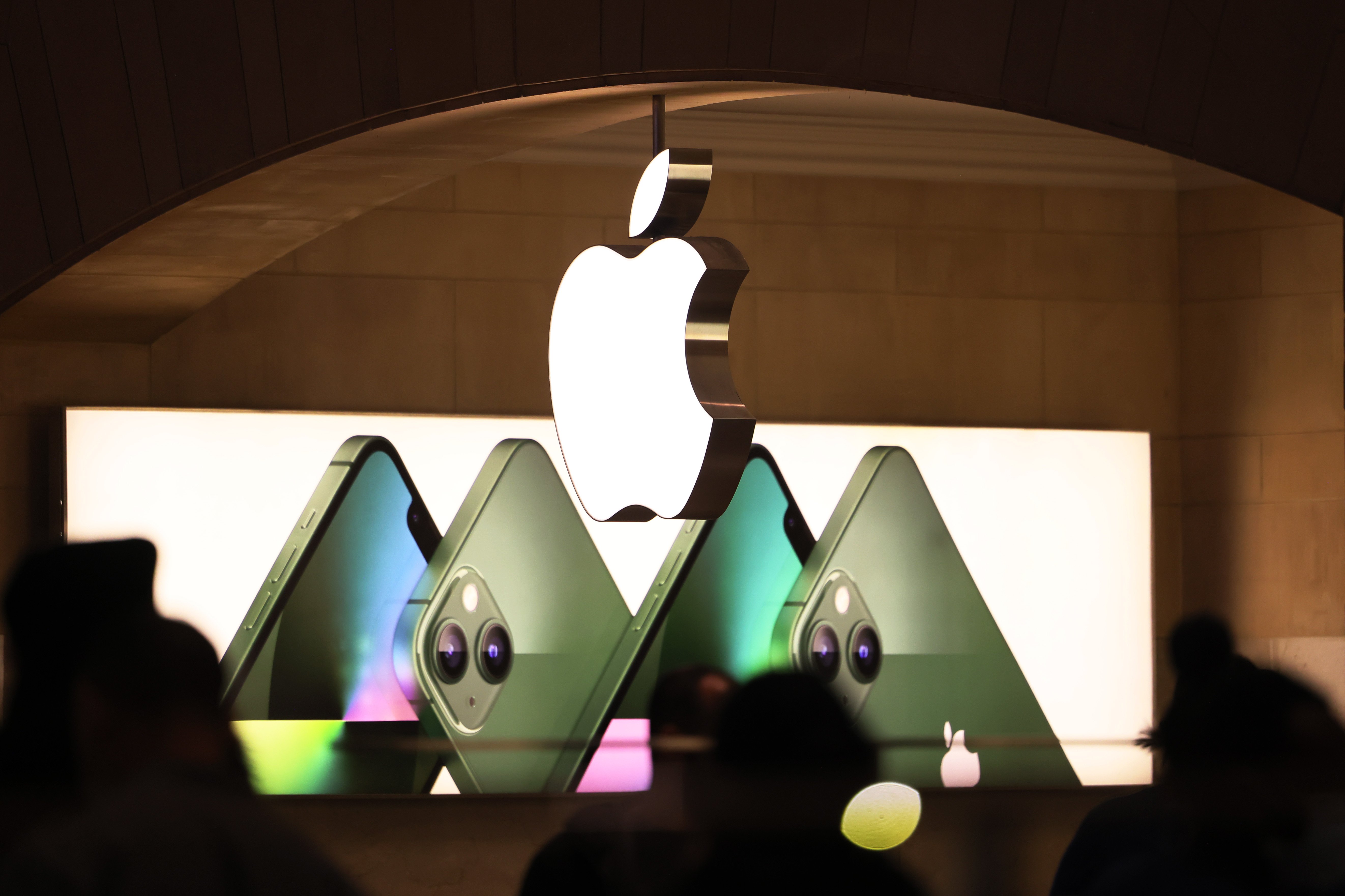 The inside of an Apple Store shows iPhones and an Apple logo.