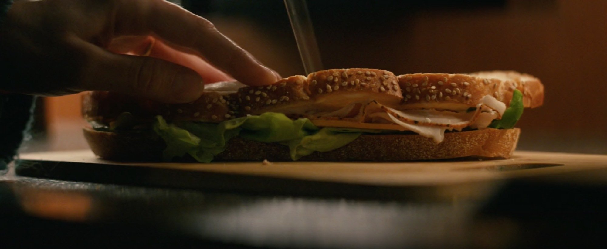A sandwich that's about to be cut in half with a knife.