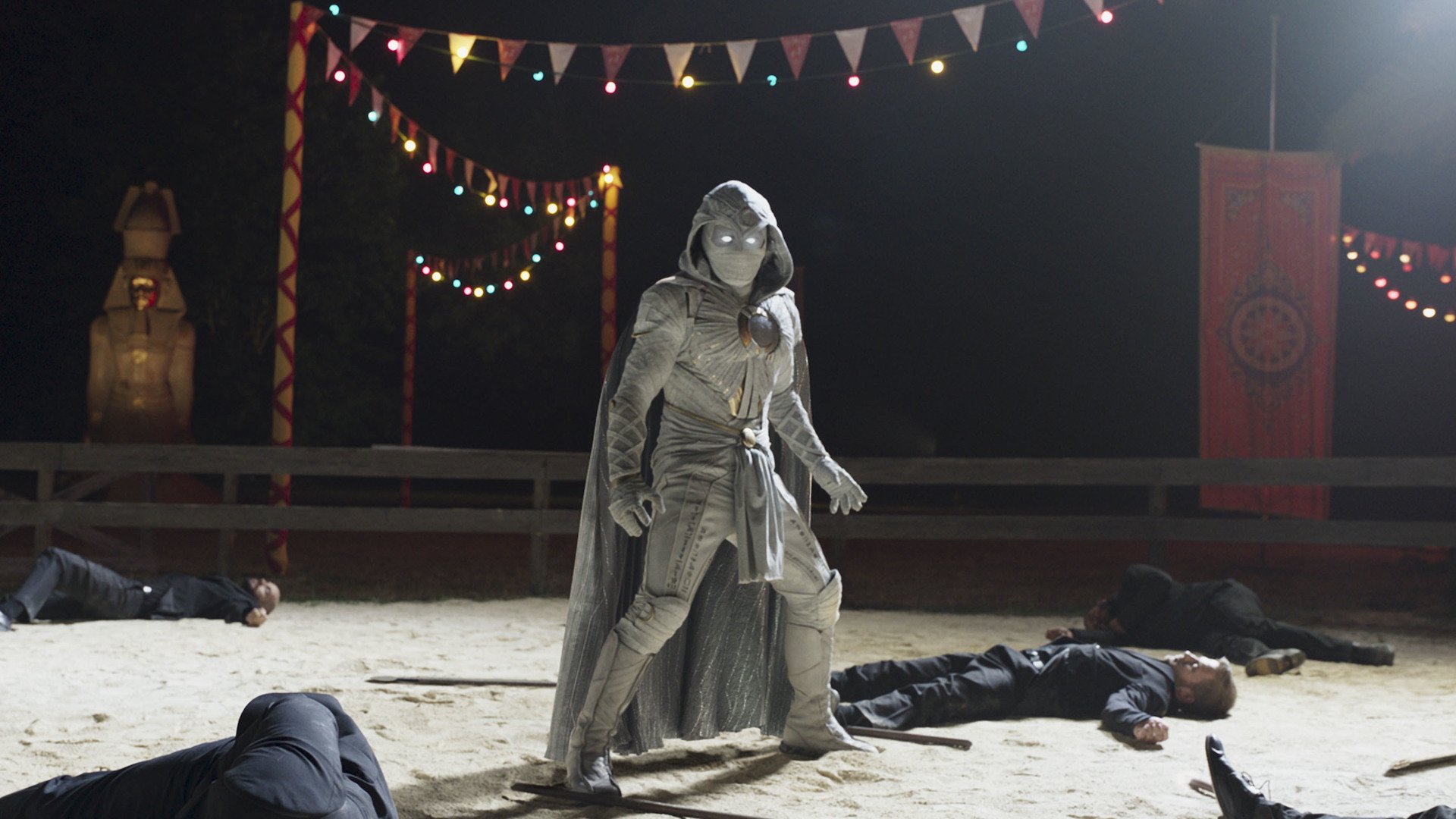 Oscar Isaac as Moon Knight standing in costume among slain enemies.