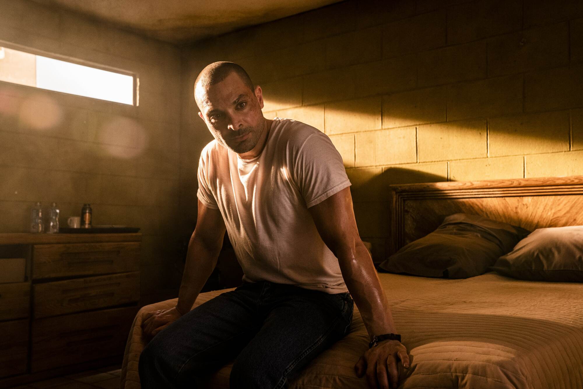 A man (Michael Mando as Nacho on "Better Call Saul") sitting on a bed in a dark room.