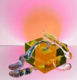 gem and stellar glass dildos resting on a box against a pink background