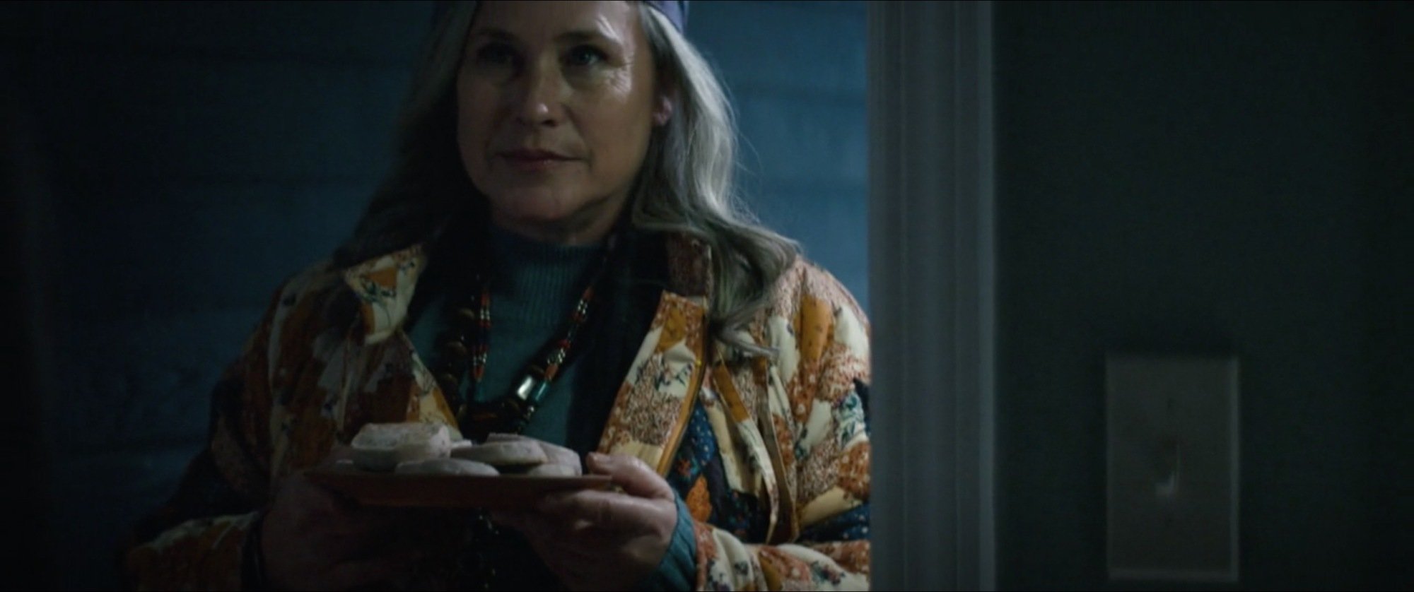 A woman (Patricia Arquette as Mrs. Selvig in "Severance") holding a plate of cookies while standing on a doorstep.