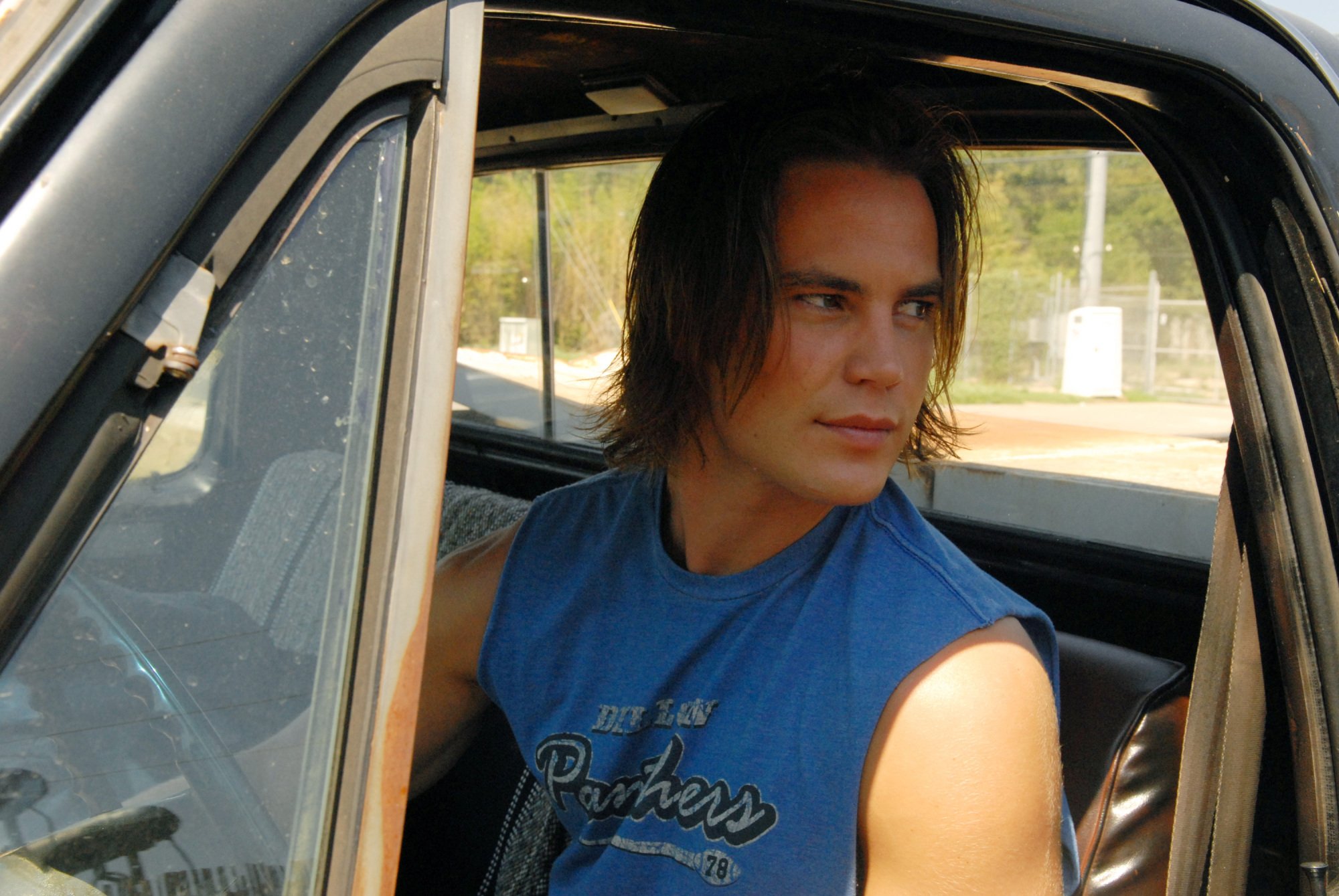 A teenage boy (Taylor Kitsch as Tim Riggins in "FNL") sitting in a truck.