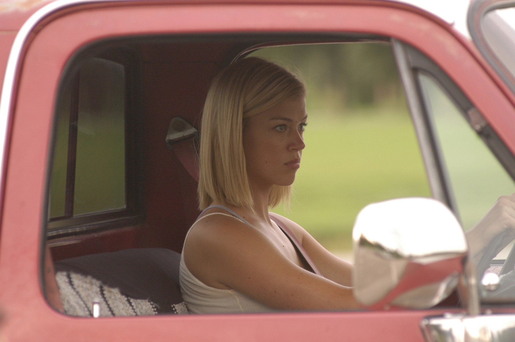 A teenage girl (Adrianne Palicki as Tyra on "FNL") in the driver's seat of a red truck.